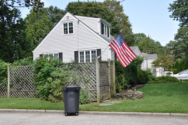 Trash can in front of house by Shutterstock.