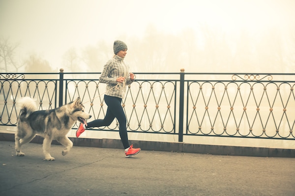 Woman running with dog by Shutterstock.