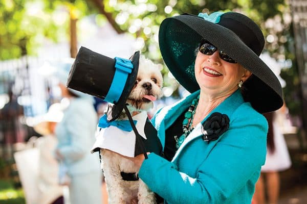 A dog and a woman dressed up in fancy hats.