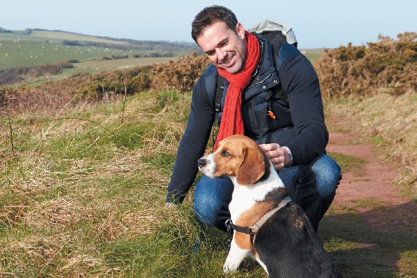 A man hiking with a Beagle dog. 