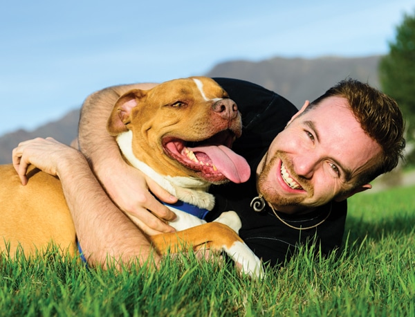 Dog and owner rolling around in grass.