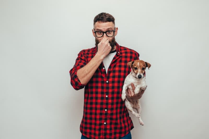 male dog owner covering his nose because his dog smells bad