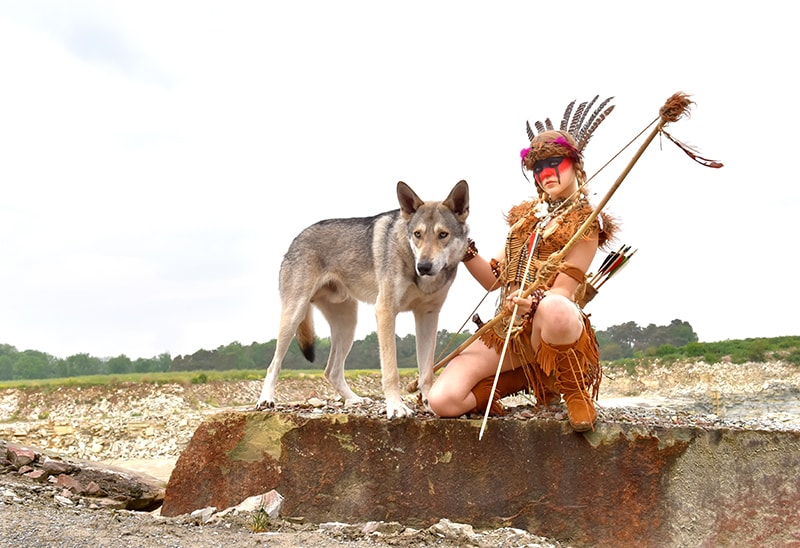 woman wearing native clothes beside a native american indian dog