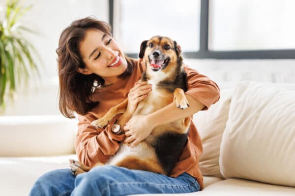 woman hugging her dog at home on the couch