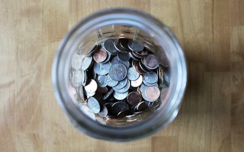 a variety of coins in a glass jar
