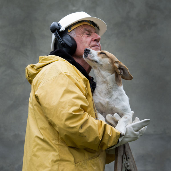 Some dogs are specially trained for search and rescue in the aftermath of an earthquake or other natural disaster. Man in safety suit holds dog in his arms by Shutterstock.