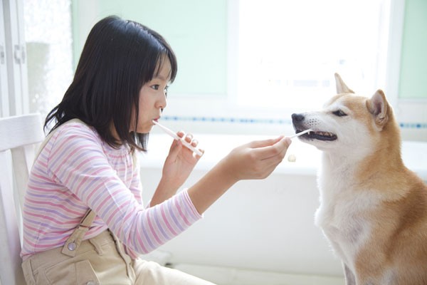 A woman brushing her teeth with her dog.