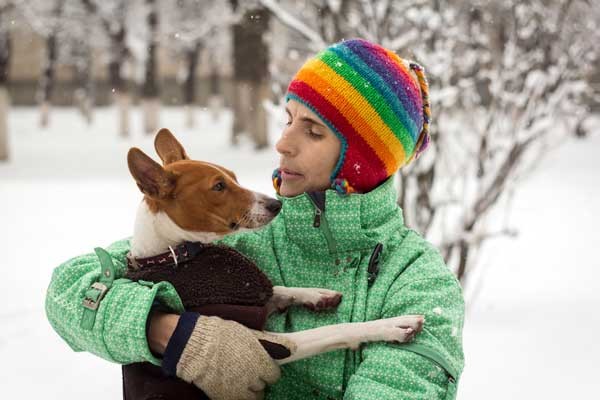 Check your dog's paws for signs of frostbite. Man and Basenji in the snow by Shutterstock