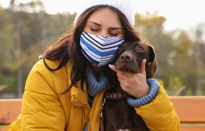 Woman in protective mask with German Shorthaired Pointer dog outdoors