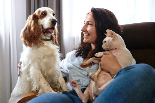 woman sitting on the sofa with dog and cat