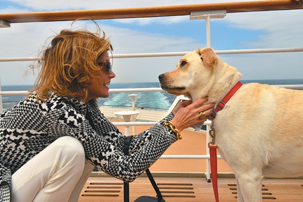 A woman with a yellow dog on a cruise ship.