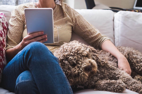 A woman on a couch with her dog. Photography by ballero/Thinkstock.