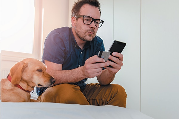 A man on a cell phone sitting next to his dog.