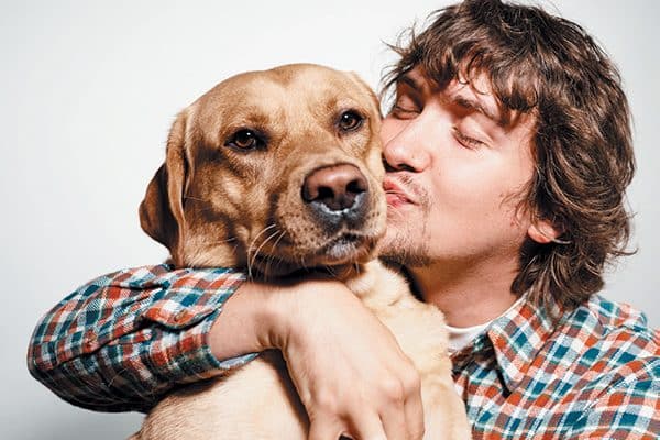 A man kissing his dog. 