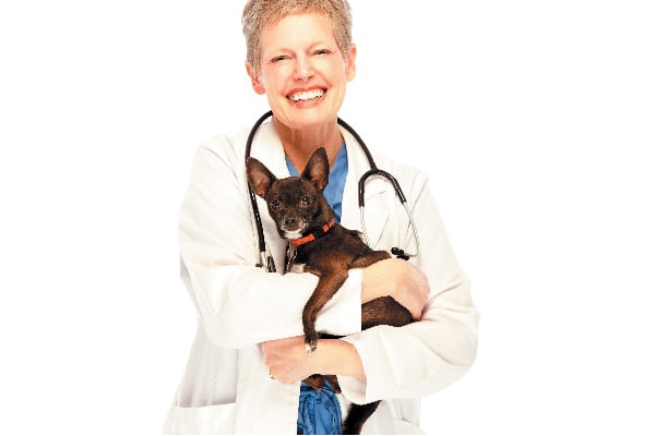 A vet hugging a dog and smiling.