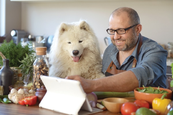 A man cooking with his dog.