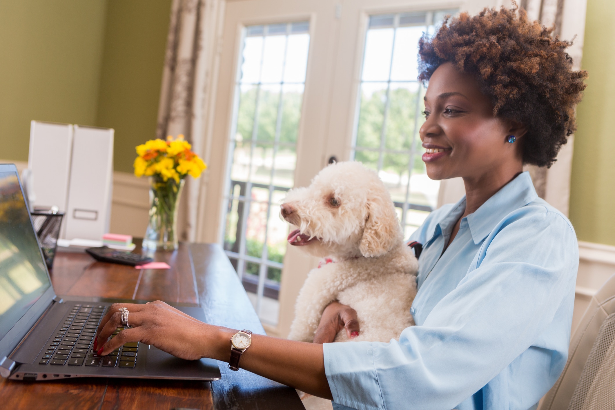 Female entrepreneur holds her dog while working in home office