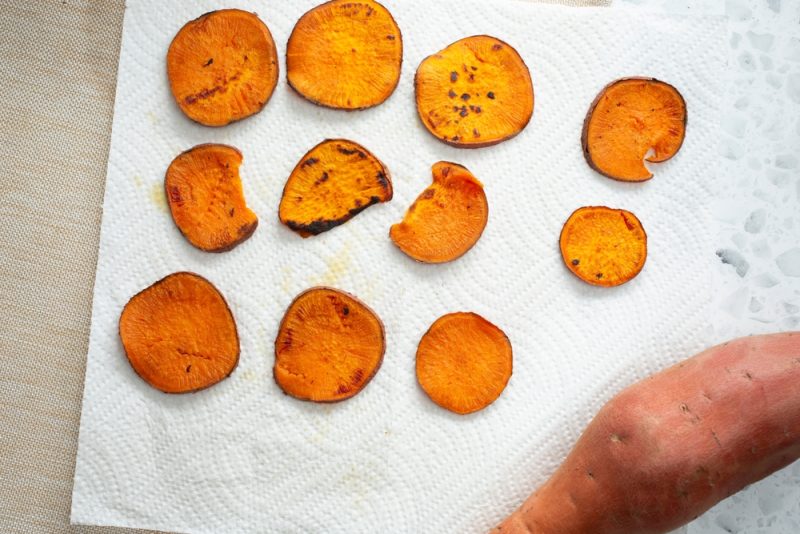 A top down view of sweet potato chips drying on a paper towel