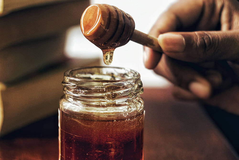 person getting some honey from the jar