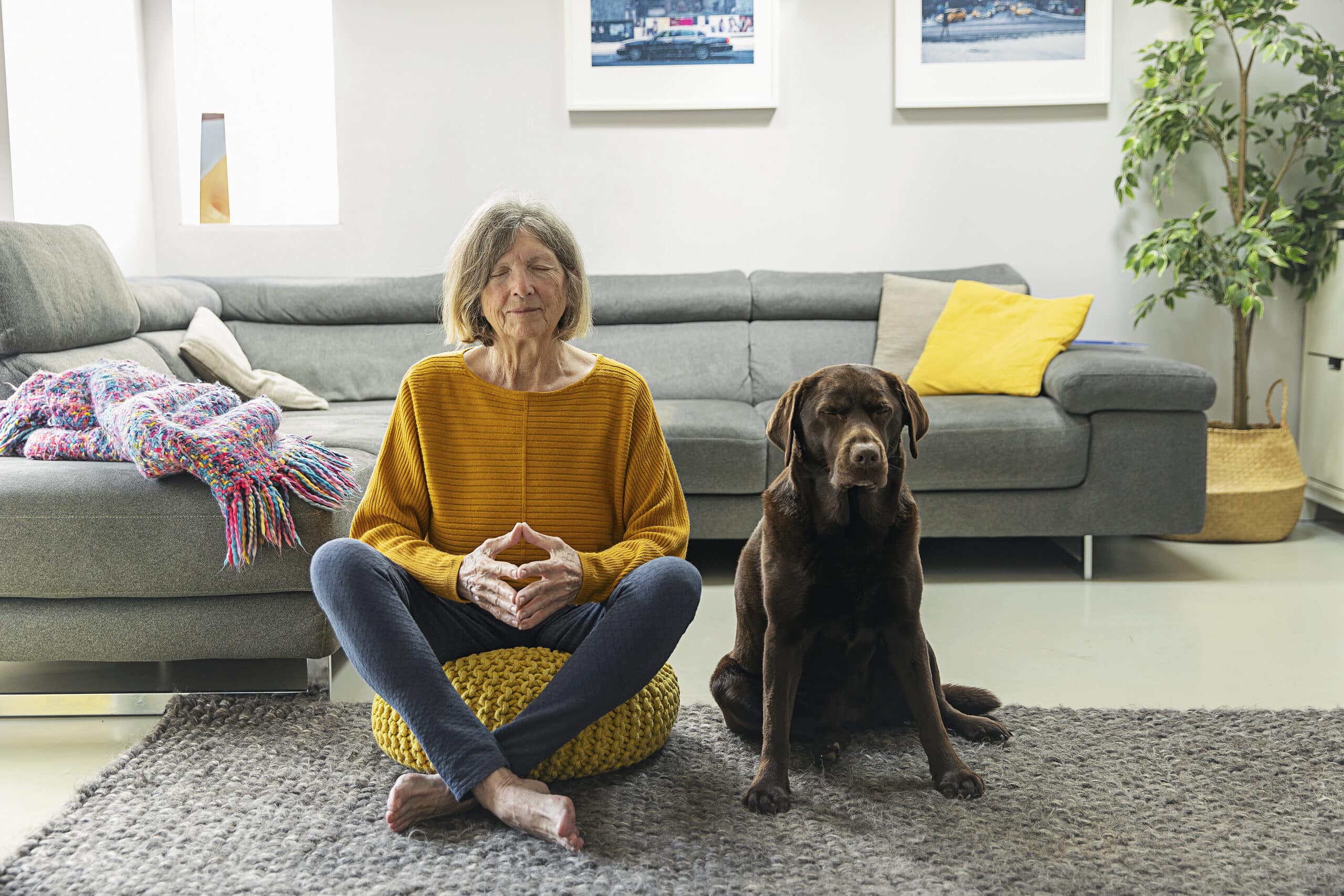 Senior woman meditating at home with her pet dog