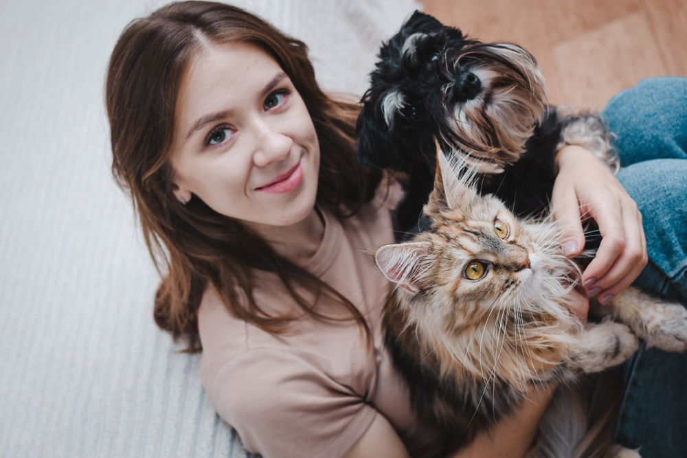 girl owner holding her dog and cat in arms