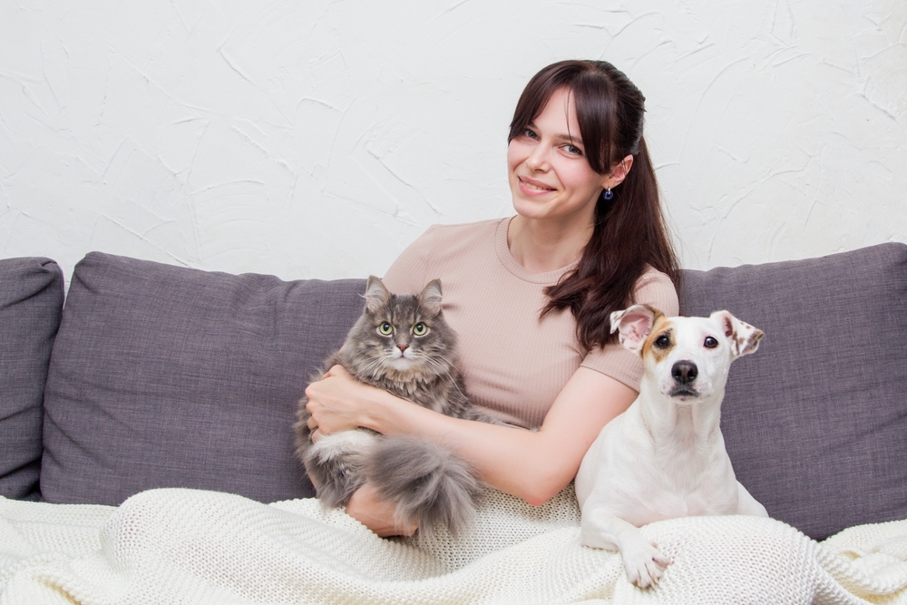 woman-sitting-on-a-couch-with-her-cat-and-dog