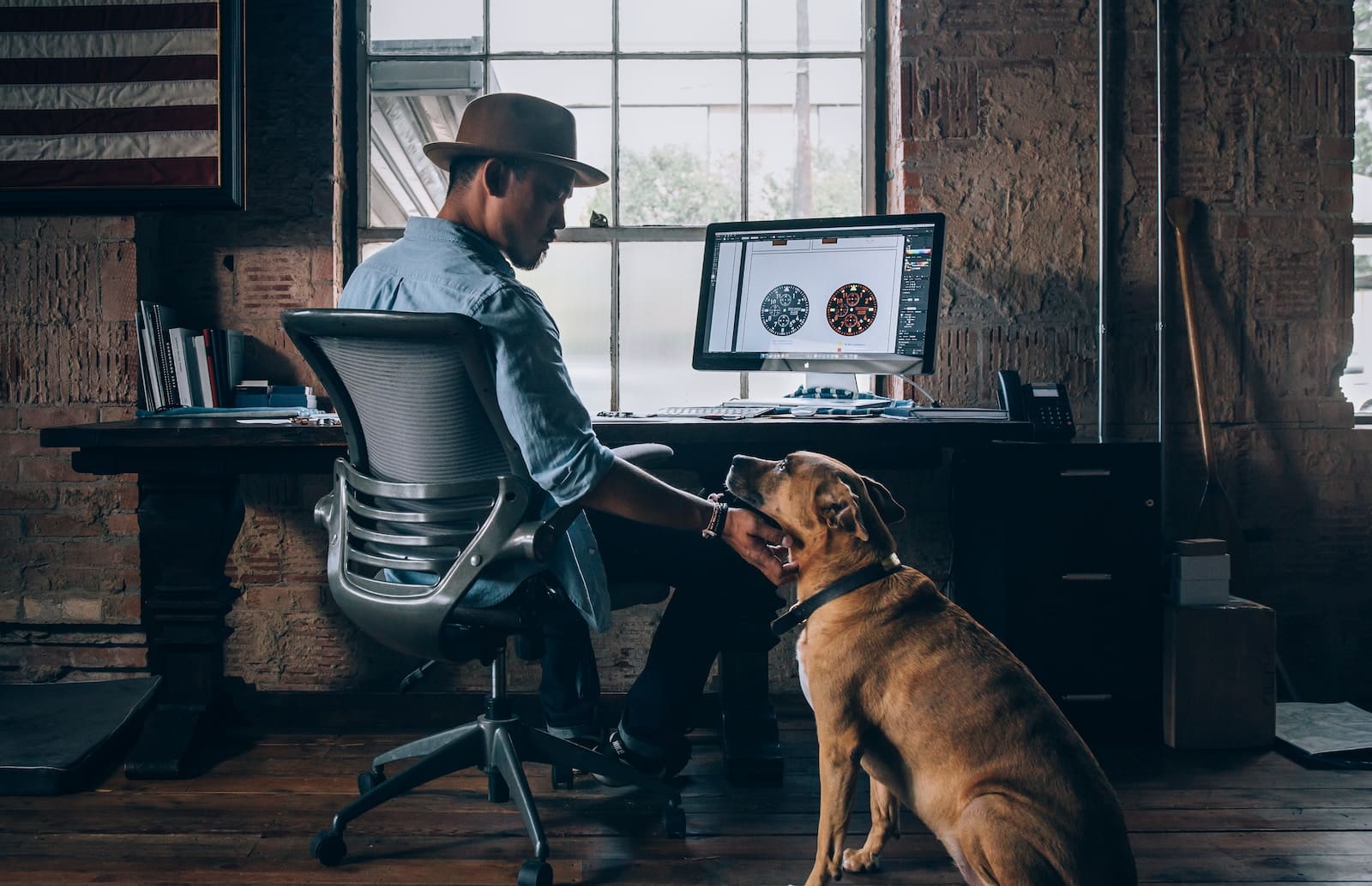 Man working on a computer while his dog is sitting next to him