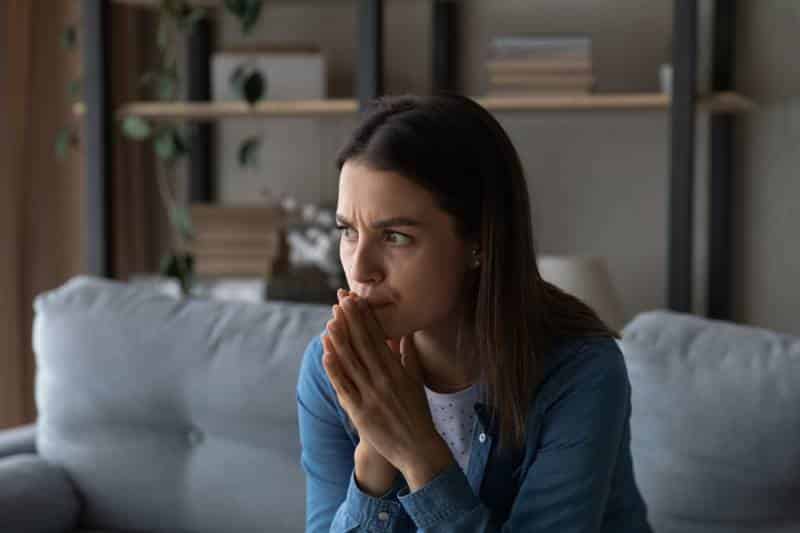 Worried young woman sitting on sofa