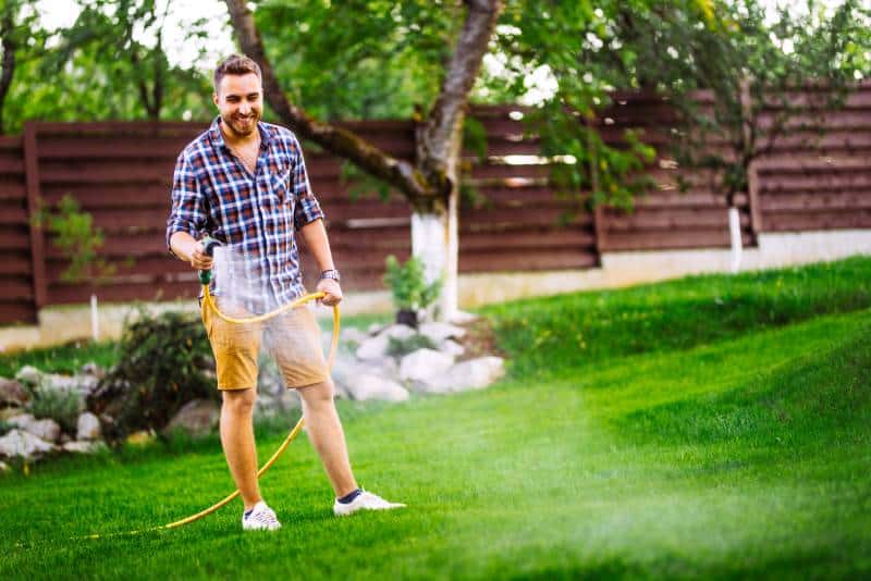 happy man with hose and watering the lawn