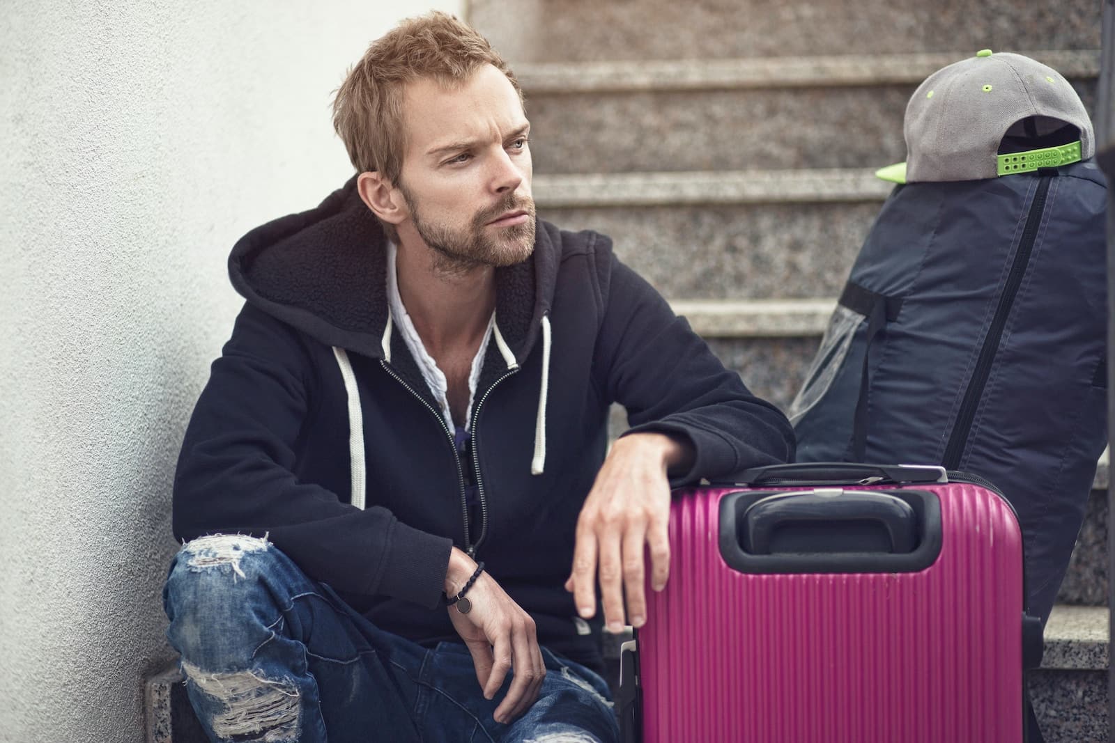 a man sitting next to a purple suitcase