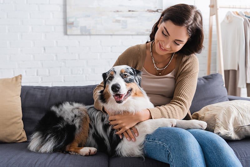 woman cuddling an australian shepherd dog