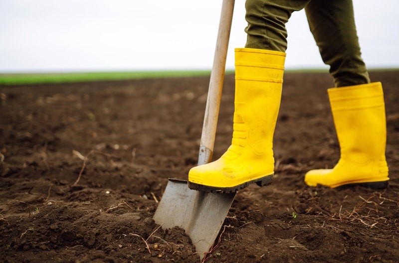 woman digs soil with shovel