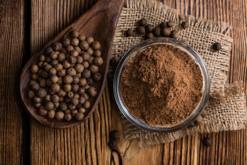 dried and powder allspice on wooden background