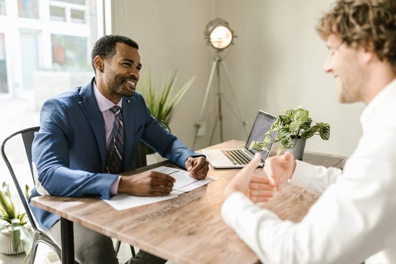 men sitting at table smiling discussing insurance