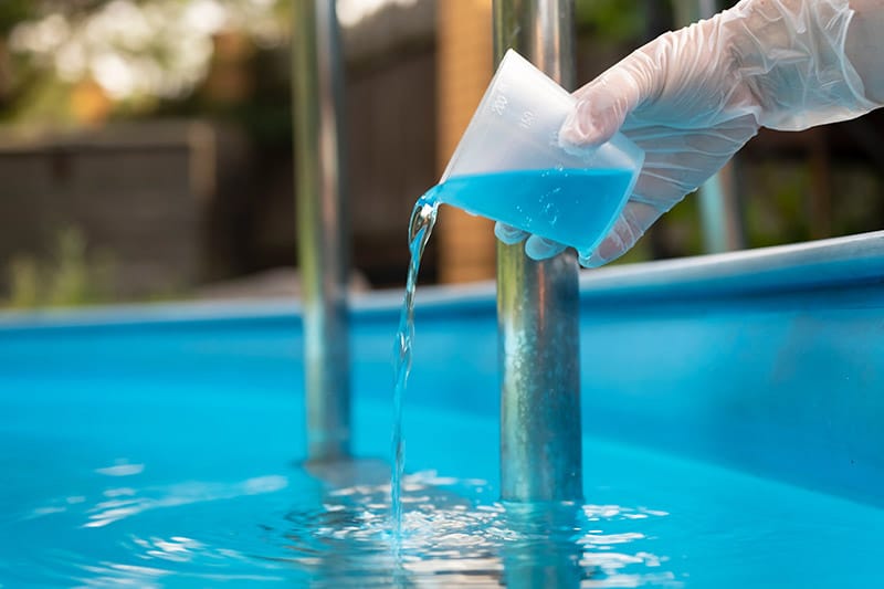 person pouring pool cleaner into the pool