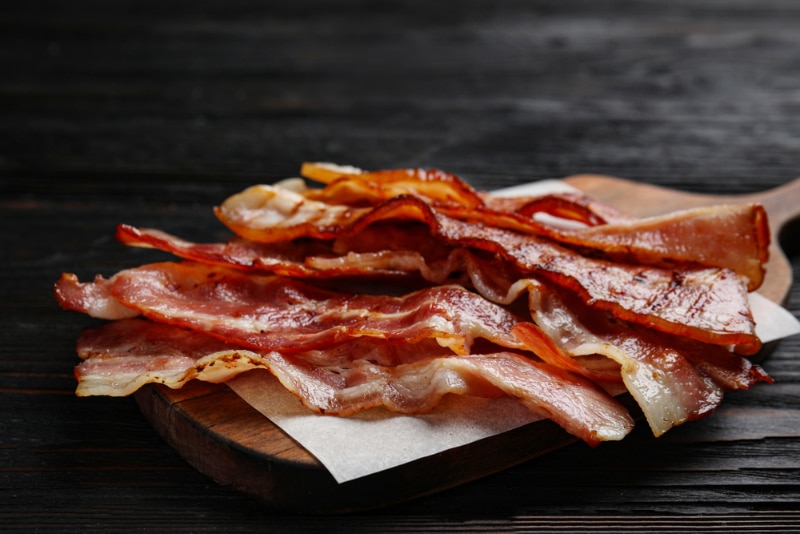 tasty fried bacon on chopping board