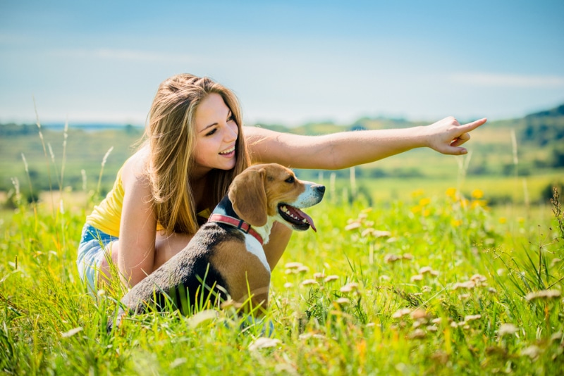 young woman with her dog pointing at something