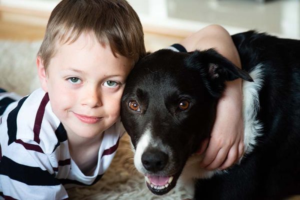 A cute little boy with ADHD plays and poses with his loyal pet dog