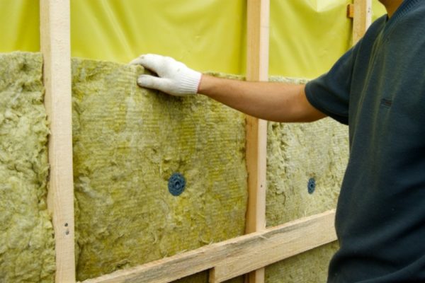 Construction worker putting in insulation material on a wall