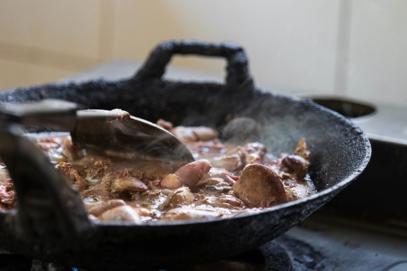 Cooked chicken livers and gizzards in hot cast iron pan