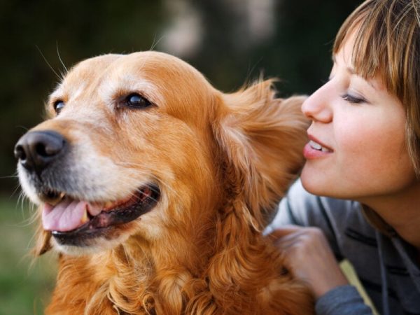 Girl whispering in her dog's ear in the park