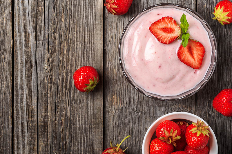 Homemade yogurt with fresh strawberry on a wooden background