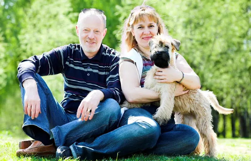 Irish soft coated wheaten terrier dog and family sitting on the grass outdoors