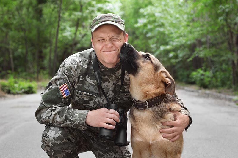 Man in military uniform with German shepherd dog