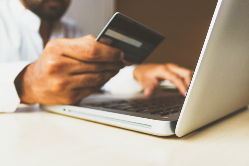 Man on computer holding a card