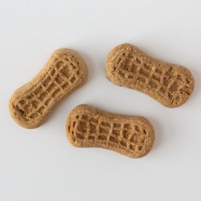 Top view of three small peanut butter flavored dog snacks on a white background