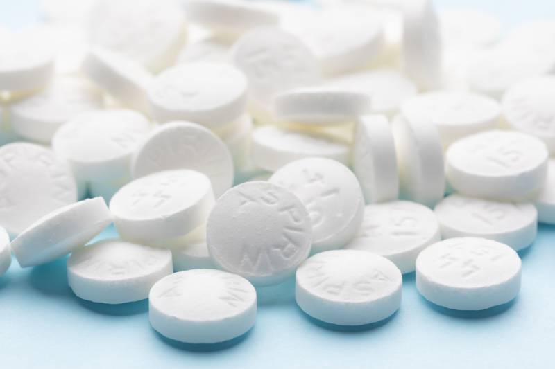 White aspirin pills on blue paper background