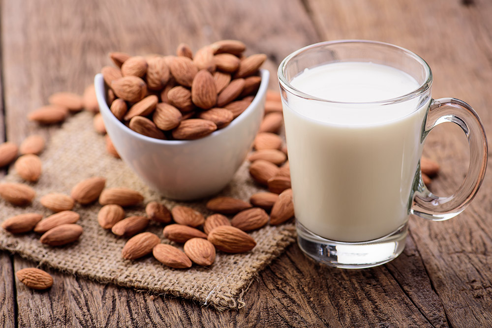 a bowl of almonds and glass of Almond milk
