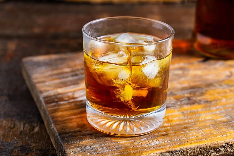 a glass of liquor on a wooden table