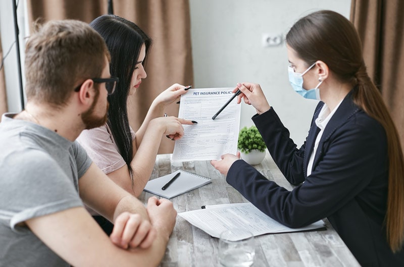 a woman explaining an insurance document to a couple